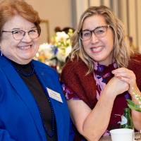 Two event guests standing at table and smiling at camera